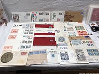 Photo showing a variety of vintage First Day of Issue envelopes arranged on a white surface, featuring different historical Canadian stamps and postal cancellations.