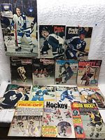 Photo of a collection of 12 vintage hockey magazines spread on a white cloth. Covers feature Toronto Maple Leafs players and various hockey themes.