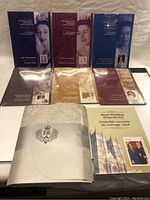 View of all six sealed Diamond Jubilee stamp folders and Royal Wedding Keepsake Kit laid out on surface