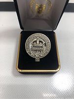 Front view of silver coloured WWI Canada For Honourable Service pin displayed in black velvet lined presentation box with gold trim and emblem on inside lid
