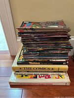 Stack of comic history and collected works books under a large stack of comics including 'Tazza of the Apes' and 'The Comics'