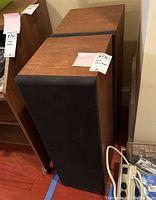 Two floor-standing KLH speakers with wood veneer finish and black fabric grilles, positioned side by side