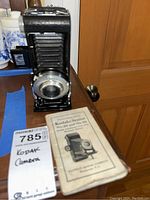 Image of Kodak Senior 620 camera folding bellows extended with instruction manual on table