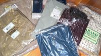 Multiple packaged men's clothing items including shirts and pants on a wooden surface.