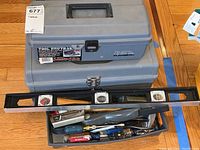 Closed and open top gray plastic Tool Brute 24 tool box showing tools inside including hammer, screwdrivers, and level