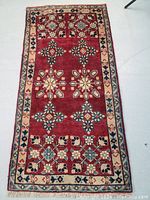 Full view of the rectangular Persian rug showing the red ground with floral and snowflake motifs, surrounded by patterned borders.