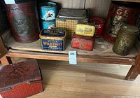 Overall view of multiple antique tins on wooden shelving and floor