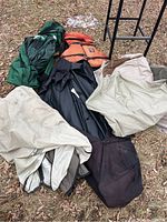 Camping gear laid out on ground including canopy fabric, life jackets, and foldable frame.