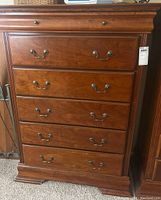 Front view of the dresser showing five drawers with metal handles, displaying the wood grain and classic styling.