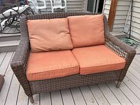Front view of 2-seat sofa showing wicker frame and orange cushions