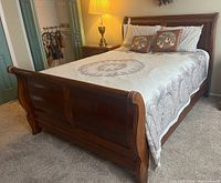 Full view of assembled sleigh bed frame with quilt and pillows