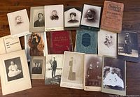 Group of antique photographic portraits, some with studio imprints, laid out on wooden table