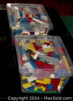 Two clear plastic containers filled with assorted LEGO bricks stacked on top of each other