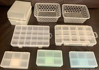 Top view of 8 plastic storage containers and organizers arranged on a brown surface showing various sizes and compartment layouts.