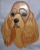 Front-facing close-up image of the carved wooden Cocker Spaniel head, showing the smooth finish of wood pieces forming the ears, eyes, nose, and fur.