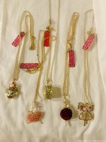 Five new Betsey Johnson gold-tone necklaces with distinctive large pendants with crystals and beads, displayed on white background.