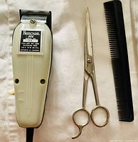 Front and side views of Renown Ace hair clipper with barber scissors and comb laid flat on white background.