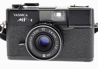 Front view of Yashica MF-1 camera showing lens, viewfinder, flash, and branding.