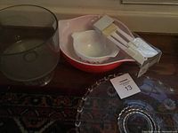 Photo showing a gray mixing bowl, three red Pyrex mixing bowls nested, white glass parfait serving piece, and new white baking spatulas in packaging.