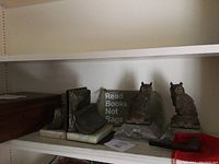 Photo showing entire lot including owl bookends, metal bookends, wooden cigar box, smoking pipe and red bag, and sign with text.