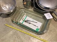 Photo of glass Pyrex casserole dishes with metal can opener on top, partial view of sifter and strainer visible around edges