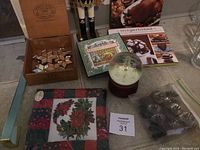 Overview of holiday items including King Nutcracker, star ornaments, snow globe, cookbooks, and table topper on a table.