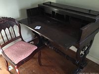 Full view of mahogany desk with matching ladies chair beside it, showing carved legs and interior compartments of the desk.