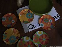 Image showing the green tray on Crate & Barrel box with six colorful floral plastic plates arranged around it.
