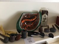 8 smoking pipes arranged with green and orange ceramic ashtray, cigar box, pipe cleaners, and wine opener.