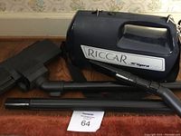 Riccar Supra Quik backpack vacuum cleaner with hose and attachments spread on floor