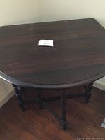 Overview of solid wood drop leaf table with one or both leaves down, showing dark wood surface with scratches.