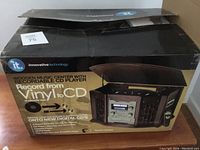 Box showing the brand Innovative Technology and product image of the wooden music center with audio components.