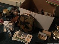 Overall view of assorted collectibles including oriental gong, postcards, glass bottles, royal doulton cream and sugar, beer mugs, vintage View Master toy.