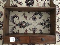 Top view of the wooden wall shelf showing two shelves and two drawers with wooden knob pulls on a patterned carpet.