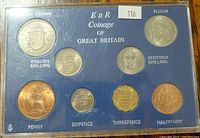 Top side of blue case with seven coins mounted and labeled including Crown, Florin, two Shillings, Penny, Sixpence, Threepence, and Halfpenny