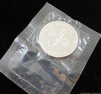 Photo showing front side of sealed coin featuring Silver Wedding design with inscriptions 'SILVER WEDDING ONE DOLLAR 1972' and royal imagery