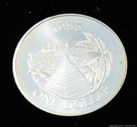 Obverse side of the coin showing 1985 date and one dollar value with pyramid, ship, and palm tree design.