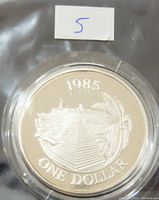 Front side of the 1985 Bermuda $1 proof coin showing the ship, pyramid and palm tree with year and denomination.