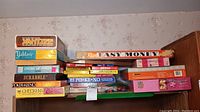 Stack of board game boxes including Yahtzee, Scrabble, Pokeno, Poker-Keno, Checkers, Easy Money, Newly Wed Game