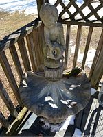 Top view showing child figurine holding a jug, positioned above a large scallop shell-shaped basin for water collection.