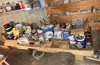 View of the main workbench area with various boxes and jars containing nails, screws, and hardware parts arranged on a wooden plank