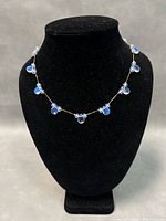 Front view of the necklace on a bust showing the arrangement of the crystal clusters along the gold filled chain.