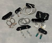 Full view of all eight pairs of earrings on black display cards showing variety of styles and sizes.