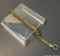 Full view of the chain bracelet on a display stand showing the woven design and clasp.