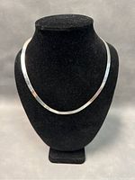 Front view of the full 19-inch sterling silver herringbone chain necklace on a display bust, showing the flat polished surface and shine.