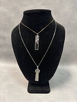 Two necklaces displayed on a black velvet stand showing the pendants and chains hanging naturally.