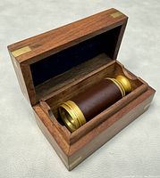 Open wooden box interior lined with dark blue velvet and telescope inside