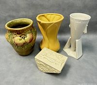 Photo shows all four pottery items together: fruit vase with raised apples, yellow Czech Atomic Style vase, white geometric vase, and covered butter dish.