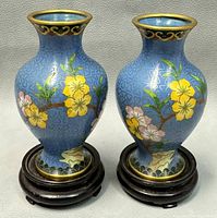 Pair of blue cloisonné enamel bud vases with floral designs and wooden bases on gray background