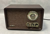 Front view of the Victrola vintage style radio showing the wooden cabinet, speaker grille, dial tuner, and control knobs.